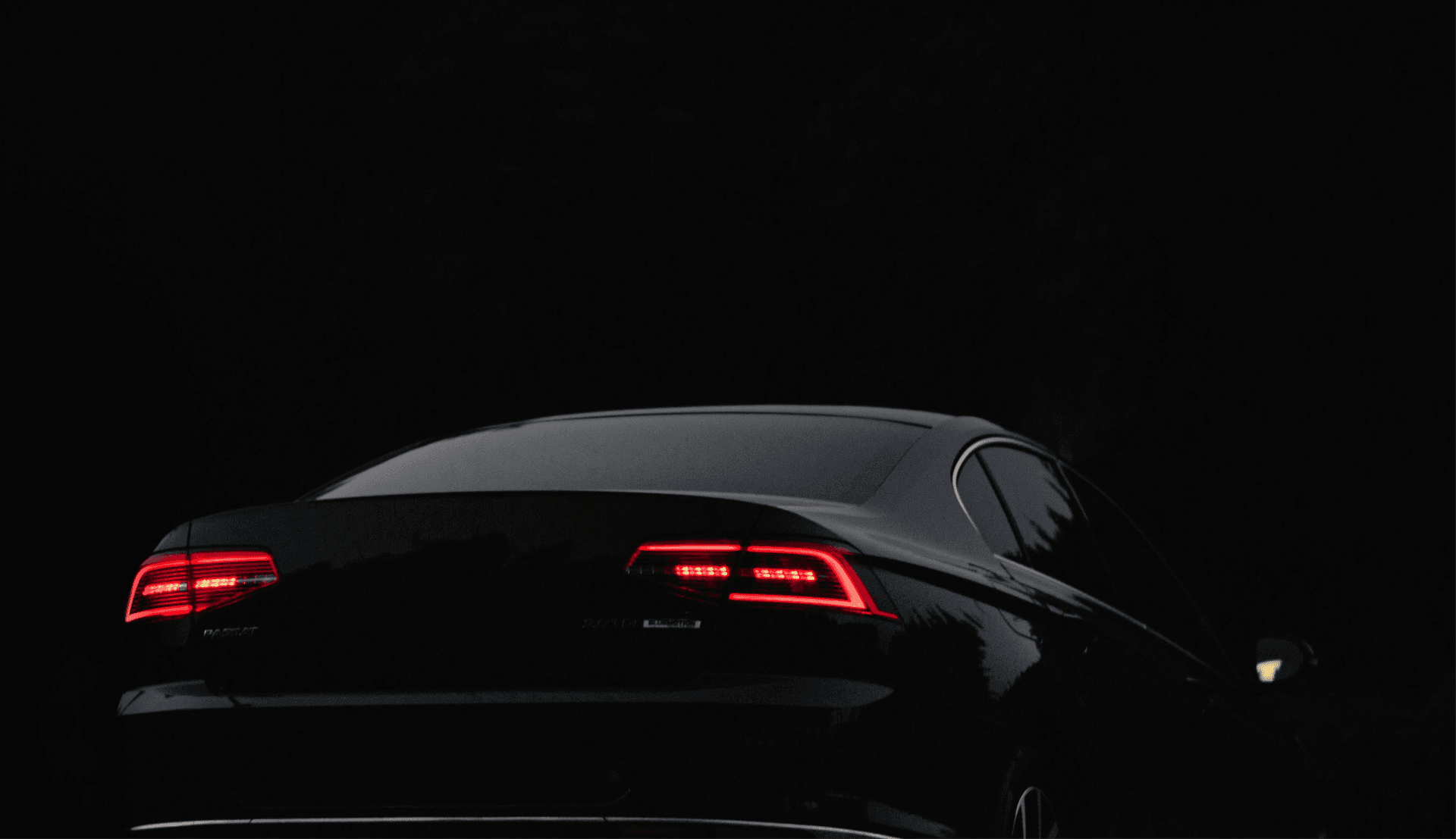 Dark luxury car with glowing red taillights
